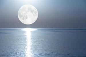 Vollmond mit einer Mondbahn, die sich im Spiegel des Meeres widerspiegelt. foto