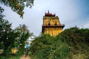 mandalay, myanmar - 7. januar 2019 - einheimische frau, die zu den touristen geht, um die handgefertigten produkte am nanmyin-wachturm oder am schiefen turm von inwa anzubieten foto