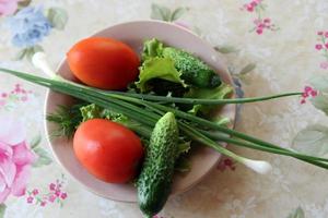 Tomaten und Gurken auf einem Teller mit Gemüse und Frühlingszwiebeln foto