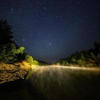 kleiner see unter sternen nachts mit nebligem dampf im sommer foto