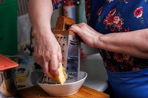 Nahaufnahme einer älteren weißen Frau, die Käse reibt foto