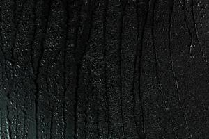 Wassertropfen auf flacher schwarzer Gummioberfläche Makrohintergrund mit Flecken foto