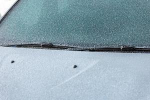 Frost bedeckte weiße Motorhaube, Scheibenwischer und Windschutzscheibe - Nahaufnahmehintergrund mit selektivem Fokus foto