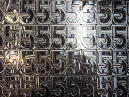 Glänzende metallbearbeitete Ziffern 5-Platten, die eng mit Ziegeln gedeckt sind - Vollbildhintergrund foto