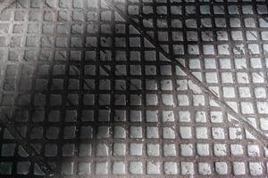 Alte industrielle Bodenfliesen aus Gusseisen mit kariertem, rutschfestem Muster - Fabrikhintergrund foto
