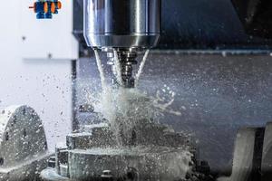 ein Prozess des industriellen Nassfräsens in einer 5-Achsen-CNC-Maschine mit Kühlmittelfluss unter Druck und gefrorenen Spritzern foto