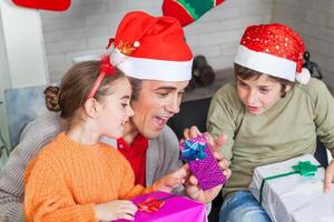 Vater mit zwei Kindern öffnen Weihnachtsgeschenke