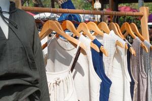 Kleiderständer mit Sommerkleidern aus Baumwolle auf Kleiderbügeln. Vitrine mit Kleidung auf dem Straßenmarkt. foto