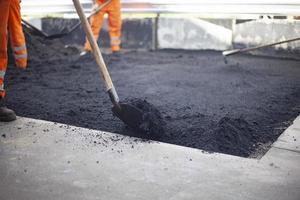 Arbeiter legt Asphalt. Reparatur der Straße. Oberfläche schaffen. Reparaturarbeiten in der Stadt. foto