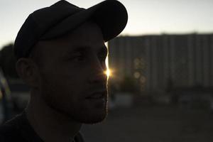 Typ mit Mütze bei Sonnenuntergang. Mann auf der Straße. foto