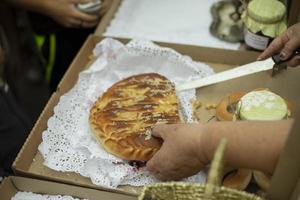 leckerer Kuchen auf der Straße. Süßes Essen. Großmutter schneidet Gebäck mit Messer. foto