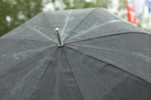 schwarzer Regenschirm im Regen. großer Regenschirm bei schlechtem Wetter. Regentropfen auf schwarzem Stoff. foto