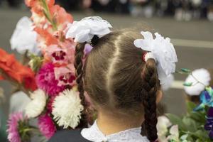 Kinder am Tag der Erkenntnis. Erstklässler gehen zur Schule. Kinder mit Blumen für Lehrer. foto