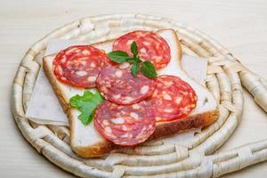 Salami-Sandwich auf Holzbrett und Holzhintergrund foto