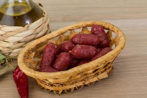 Mini-Salami in einem Korb auf Holzhintergrund foto