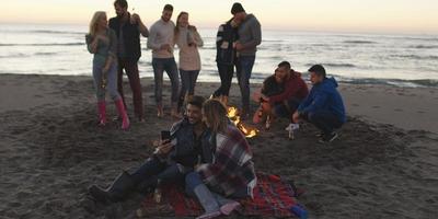 freunde, die sich am herbsttag am strand vergnügen foto