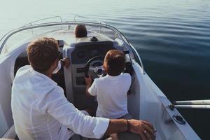 ein älteres paar in lässigen outfits mit ihrem sohn genießt es, bei sonnenuntergang auf einem boot auf see zu fahren. das Konzept einer glücklichen Familie. selektiver Fokus foto