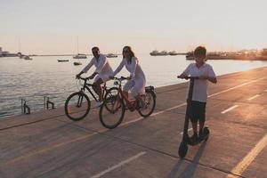 glückliche familie, die zusammen einen schönen morgen am meer genießt, eltern, die fahrrad fahren, und ihr sohn, der einen elektroroller fährt. selektiver Fokus foto