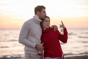 Paar umarmt und trinkt gemeinsam Bier am Strand foto