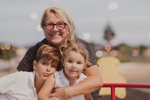 Eine ältere Großmutter spielt bei Sonnenuntergang mit ihren Enkelkindern in einem Park. selektiver Fokus foto