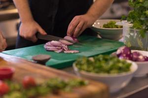 chefhände schneiden die zwiebel mit messer foto