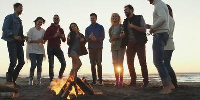 freunde, die sich am herbsttag am strand vergnügen foto