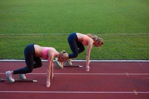 athletinnengruppe, die auf leichtathletik-rennstrecke läuft foto