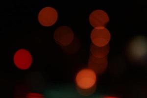 Runde rote Bokeh-Lichter auf schwarzem Hintergrund. defokussierte Lichter der Stadt foto