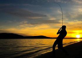 junger Mann beim Angeln bei Sonnenuntergang foto