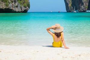 Touristin im gelben Badeanzug und Hut, glücklicher Reisender beim Sonnenbaden am Maya Bay Beach auf der Insel Phi Phi, Krabi, Thailand. wahrzeichen, reiseziel südostasien, urlaub und urlaubskonzept foto