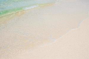 weiche welle aus blauem meerwasser und weißem sand am schönen strand. Hintergrund, Tapete und abstraktes Konzept foto