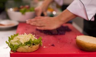 Koch schneidet Salat für Burger foto