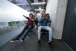 Multiethnisches Geschäftsteam, das auf Bürostühlen rast foto