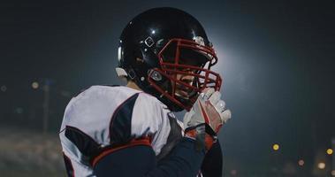 American-Football-Spieler, der einen Helm auf einem großen Stadion mit Lichtern im Hintergrund aufsetzt foto