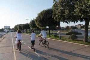 glückliche familie, die zusammen einen schönen morgen am meer genießt, eltern, die fahrrad fahren, und ihr sohn, der einen elektroroller fährt. selektiver Fokus foto