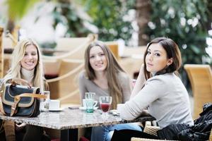 süße lächelnde frauen, die einen kaffee trinken foto