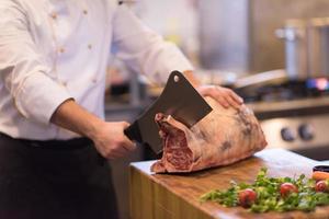 Koch schneidet ein großes Stück Rindfleisch foto