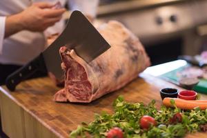 Koch schneidet ein großes Stück Rindfleisch foto