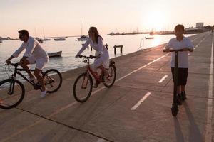 glückliche familie, die zusammen einen schönen morgen am meer genießt, eltern, die fahrrad fahren, und ihr sohn, der einen elektroroller fährt. selektiver Fokus foto