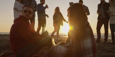 freunde, die sich am herbsttag am strand vergnügen foto