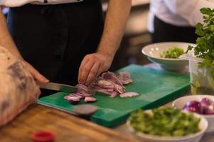 chefhände schneiden die zwiebel mit messer foto