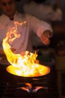 Koch macht Flamme auf Essen foto