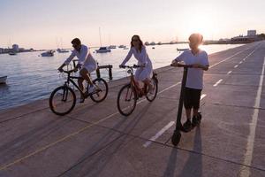 glückliche familie, die zusammen einen schönen morgen am meer genießt, eltern, die fahrrad fahren, und ihr sohn, der einen elektroroller fährt. selektiver Fokus foto