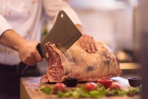 Koch schneidet ein großes Stück Rindfleisch foto