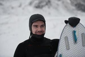 arktisches surferporträt, das ein brett nach dem surfen im norwegischen meer hält foto