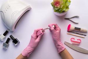 manikürist in handschuhen hält nagellack foto