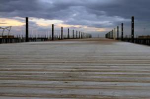 hölzerner Pier, der zu einem bewölkten Himmel führt foto