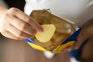 hand halten kartoffelchips mit snackbeutel foto