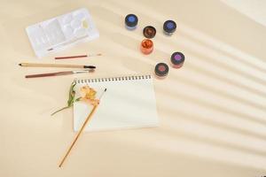 satz aquarellfarbe, kunstpinsel und papier auf einem schreibtisch foto
