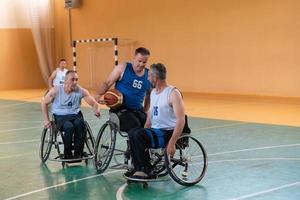 Behinderte Kriegsveteranen gemischte Rassen gegen Basketballmannschaften in Rollstühlen, die in Aktion fotografiert wurden, während sie ein wichtiges Spiel in einer modernen Halle spielten. foto